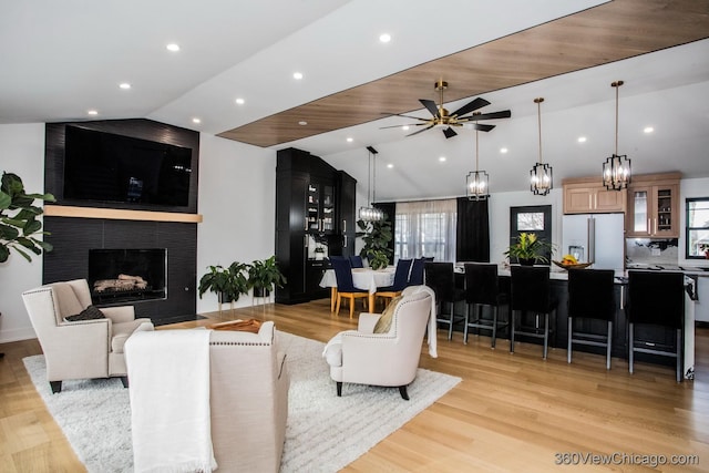 living room with lofted ceiling, recessed lighting, light wood-style floors, a ceiling fan, and a large fireplace