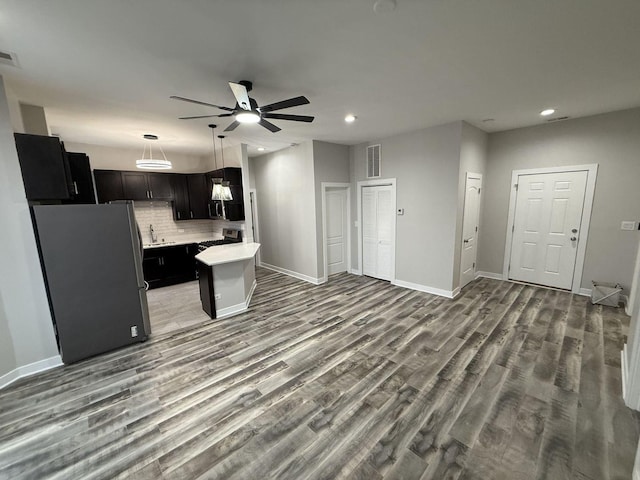 kitchen featuring appliances with stainless steel finishes, sink, decorative backsplash, ceiling fan, and light hardwood / wood-style floors