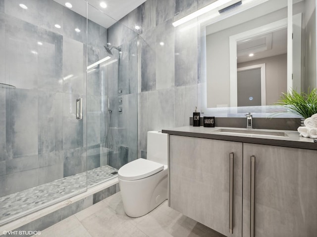 bathroom featuring vanity, toilet, a shower with shower door, and tile walls