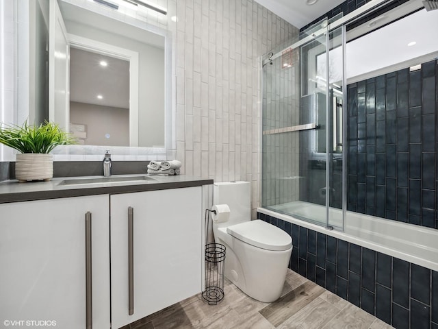 full bathroom with vanity, enclosed tub / shower combo, and toilet