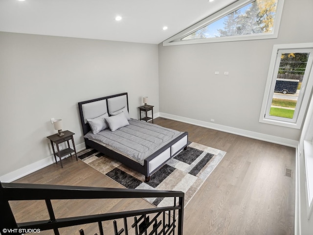 bedroom featuring multiple windows, wood-type flooring, and lofted ceiling