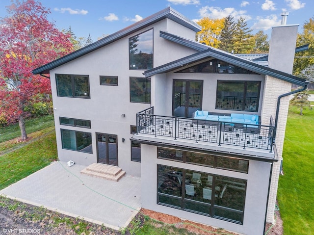 back of house featuring a patio, a balcony, and a lawn