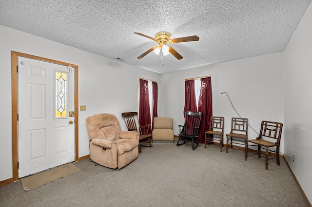 living area with ceiling fan, a textured ceiling, a healthy amount of sunlight, and carpet