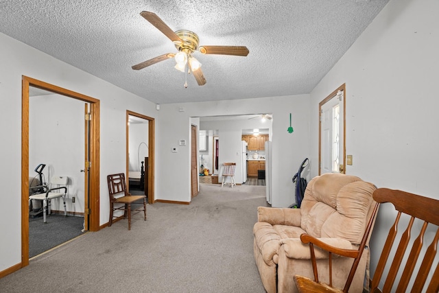 living area featuring light carpet, a textured ceiling, and ceiling fan