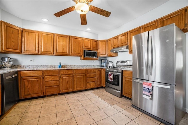 kitchen featuring light tile patterned flooring, appliances with stainless steel finishes, ceiling fan, and light stone counters