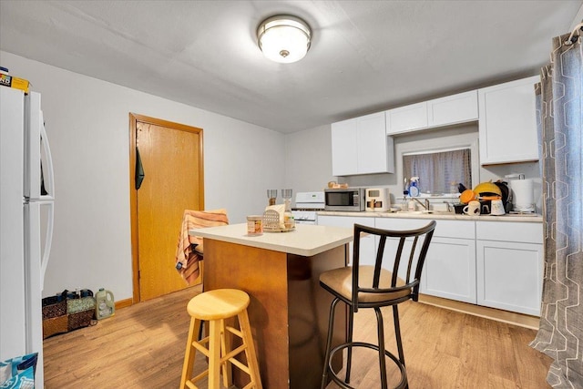 kitchen with white cabinetry, light hardwood / wood-style flooring, a breakfast bar, and white refrigerator