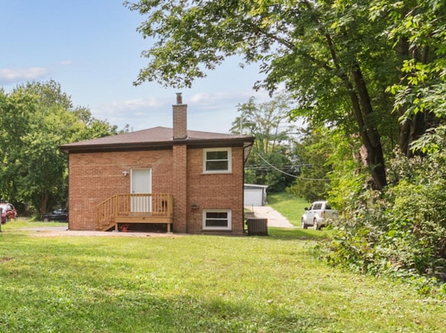 rear view of property featuring a yard and central AC unit