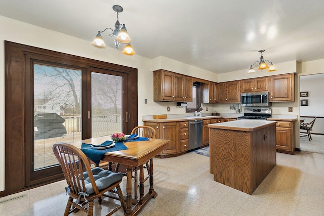 kitchen featuring stainless steel appliances, a kitchen island, a notable chandelier, and decorative light fixtures