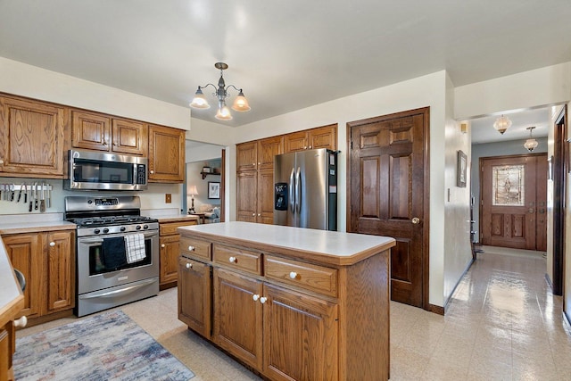 kitchen with pendant lighting, stainless steel appliances, a kitchen island, and a notable chandelier