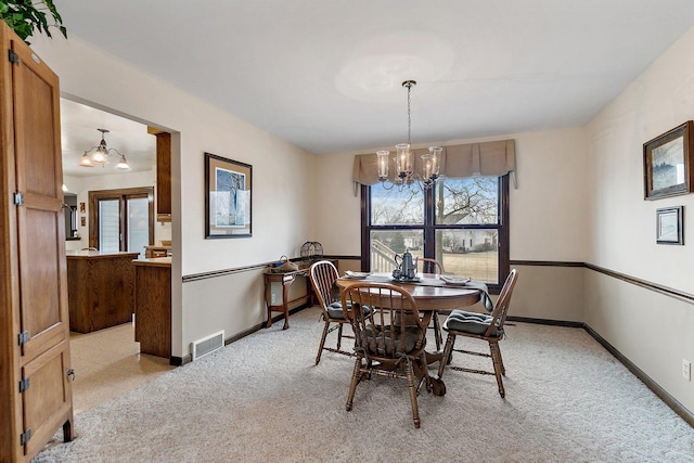 carpeted dining area featuring an inviting chandelier