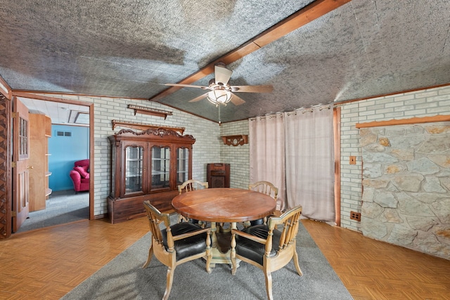 dining room featuring visible vents, vaulted ceiling, ceiling fan, a textured ceiling, and brick wall