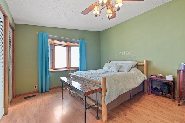 bedroom with a textured ceiling, baseboards, visible vents, and light wood-style floors