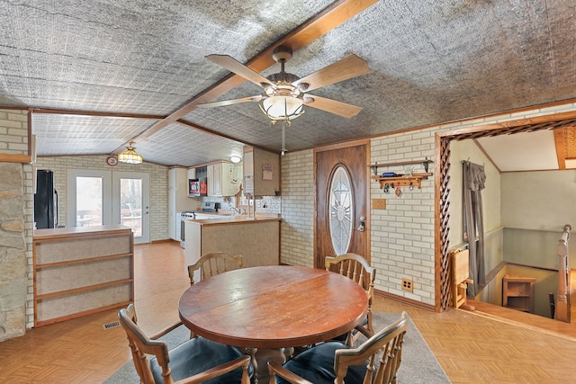 dining area featuring lofted ceiling, french doors, ceiling fan, and brick wall