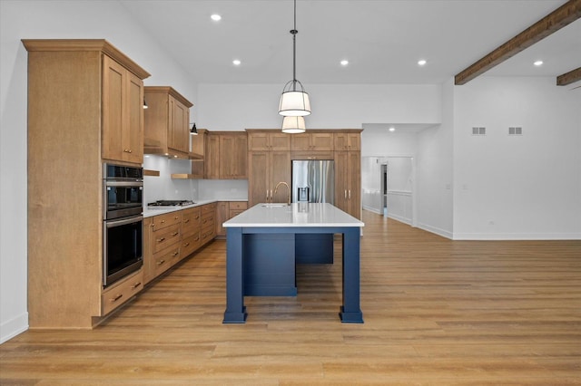 kitchen featuring a breakfast bar, hanging light fixtures, stainless steel appliances, a center island with sink, and light wood-type flooring