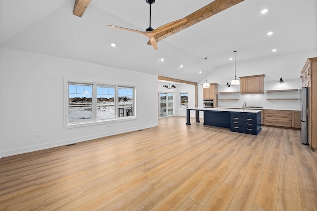 kitchen with pendant lighting, a kitchen island with sink, beam ceiling, stainless steel appliances, and light hardwood / wood-style floors