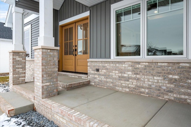 snow covered property entrance with french doors and a porch