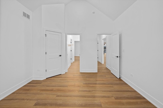 unfurnished bedroom featuring high vaulted ceiling and light hardwood / wood-style floors