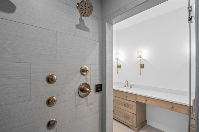 bathroom with tiled shower and vanity