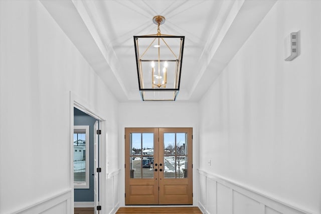 entryway with french doors, a tray ceiling, a chandelier, and hardwood / wood-style flooring