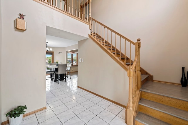 stairway with tile patterned flooring and a high ceiling