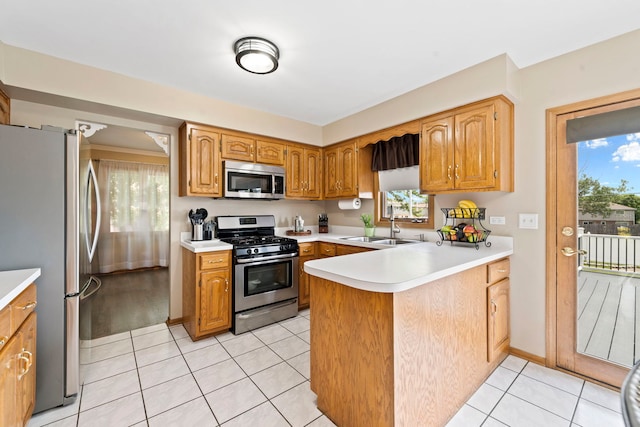 kitchen featuring stainless steel appliances, sink, light tile patterned floors, and kitchen peninsula