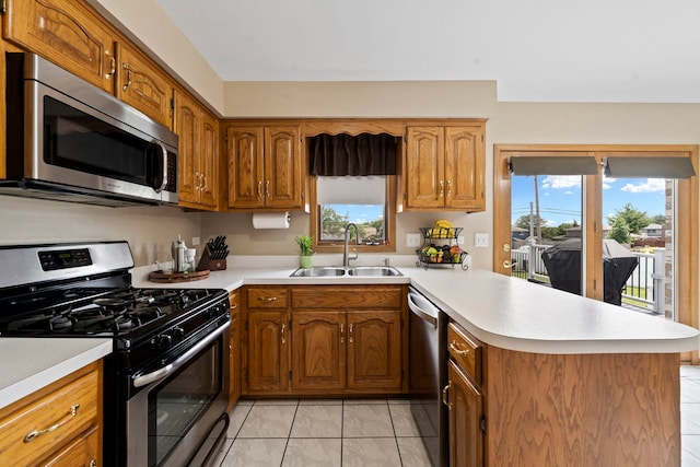 kitchen featuring stainless steel appliances, sink, light tile patterned floors, and kitchen peninsula