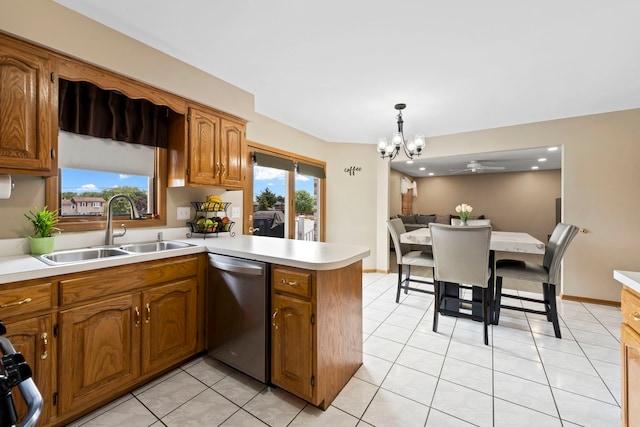 kitchen featuring pendant lighting, dishwasher, sink, light tile patterned floors, and kitchen peninsula