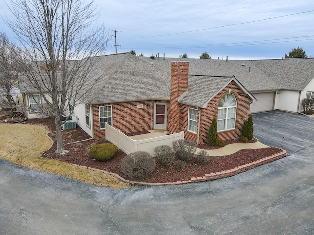 ranch-style home with central AC unit and a garage