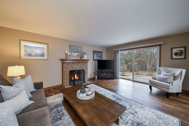 living room with a brick fireplace and wood-type flooring