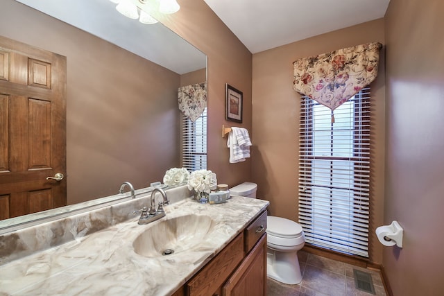 bathroom featuring tile patterned flooring, vanity, a healthy amount of sunlight, and toilet