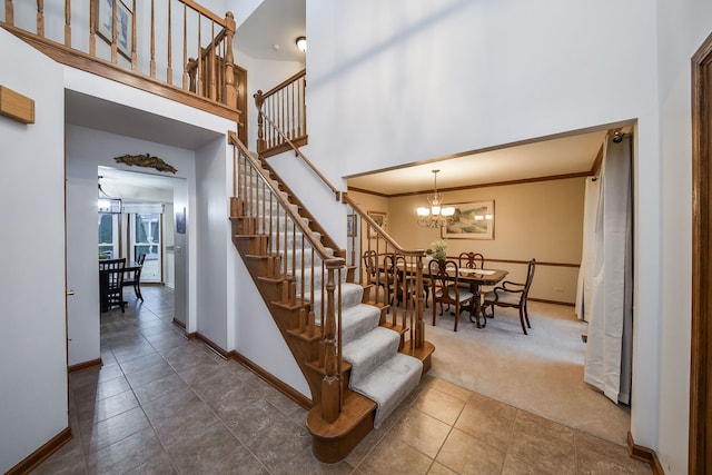 stairway featuring an inviting chandelier, a towering ceiling, ornamental molding, and carpet flooring