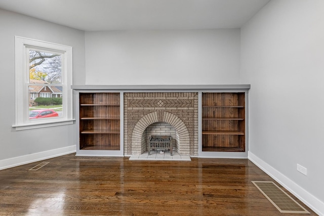 unfurnished living room with dark hardwood / wood-style flooring and a brick fireplace