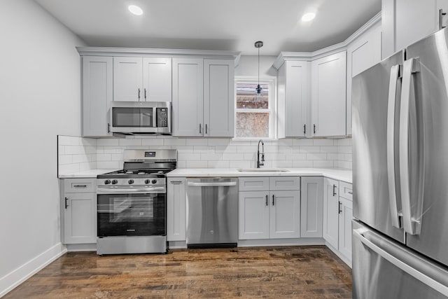 kitchen featuring pendant lighting, stainless steel appliances, sink, and white cabinets