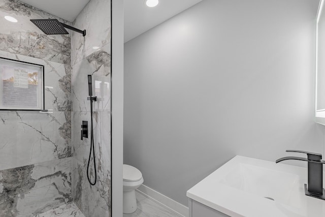 bathroom featuring vanity, a tile shower, and toilet