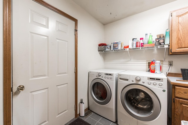 laundry room with cabinet space, washer and clothes dryer, and dark tile patterned flooring