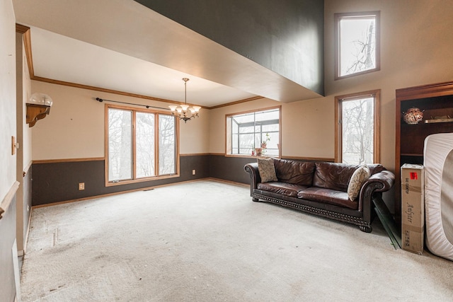 living room featuring a notable chandelier, wainscoting, carpet flooring, and crown molding