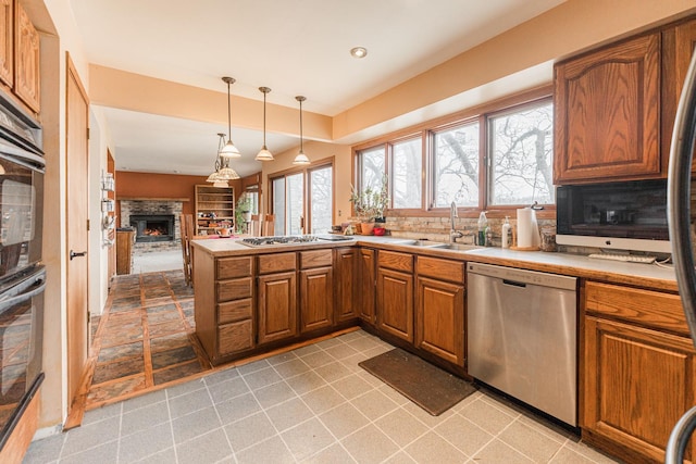 kitchen with appliances with stainless steel finishes, plenty of natural light, a sink, and brown cabinets