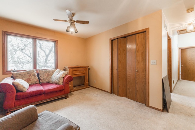 living area with light carpet, a ceiling fan, and baseboards