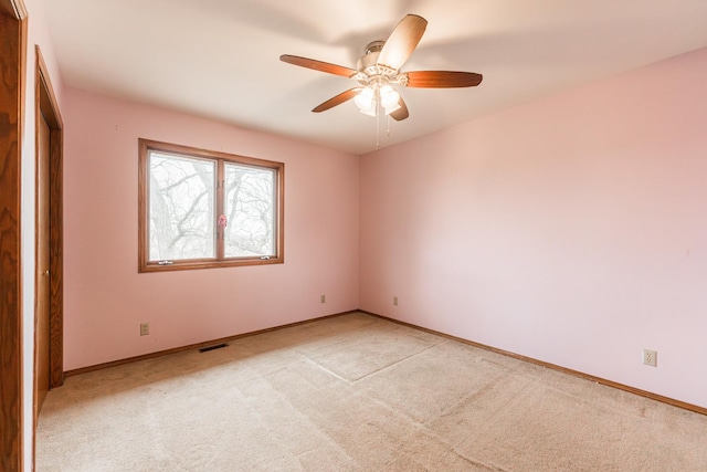 spare room featuring baseboards, a ceiling fan, visible vents, and light colored carpet