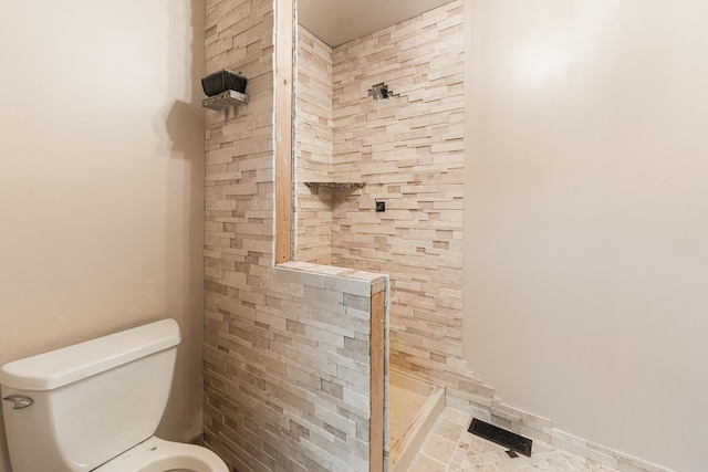 full bathroom featuring visible vents, a tile shower, and toilet