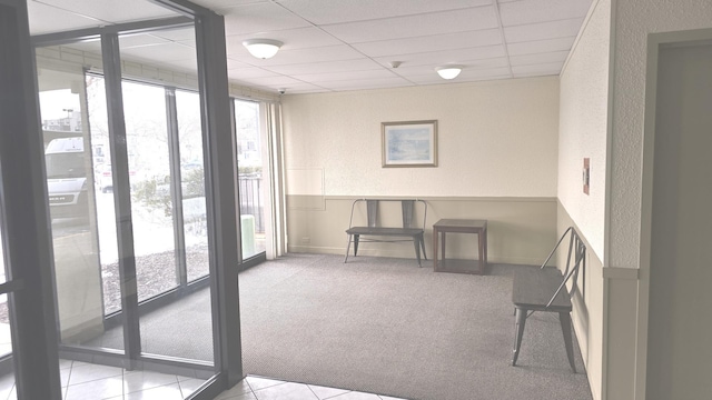 interior space featuring a paneled ceiling, floor to ceiling windows, and a wealth of natural light