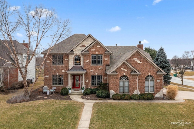 traditional home featuring a shingled roof, brick siding, a chimney, and a front lawn