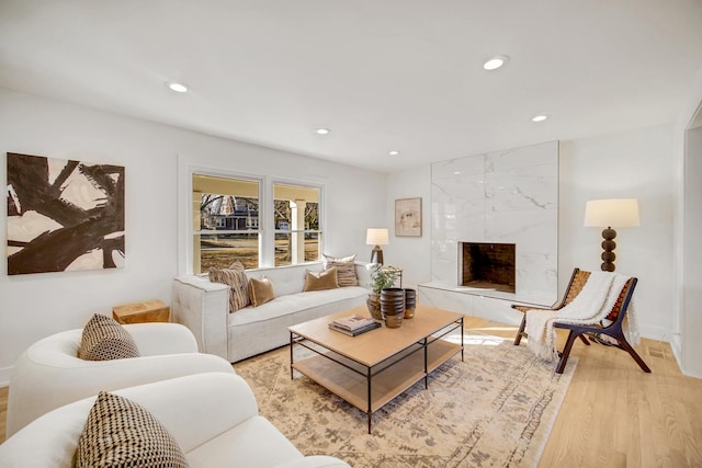 living room with a high end fireplace and light wood-type flooring