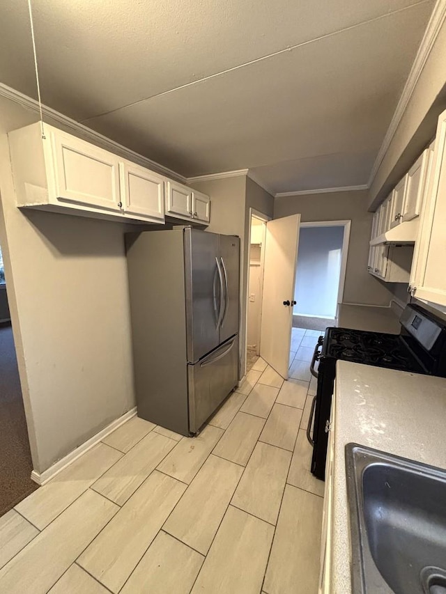 kitchen with stainless steel refrigerator, ornamental molding, range with gas stovetop, and white cabinets