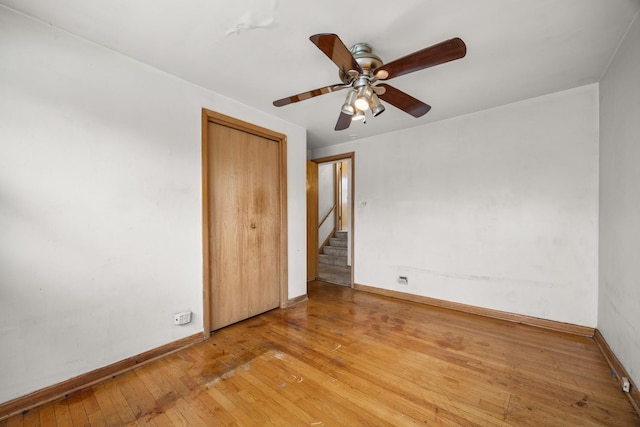 unfurnished bedroom with ceiling fan, a closet, and light wood-type flooring