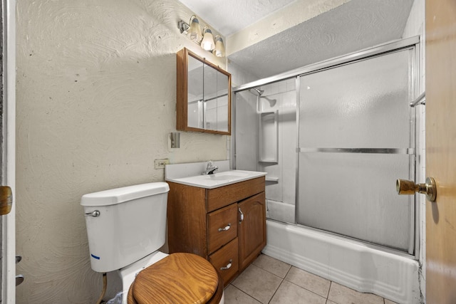 full bathroom with combined bath / shower with glass door, tile patterned flooring, vanity, a textured ceiling, and toilet