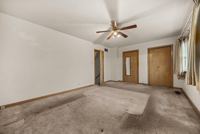 unfurnished bedroom featuring multiple closets, carpet flooring, and ceiling fan