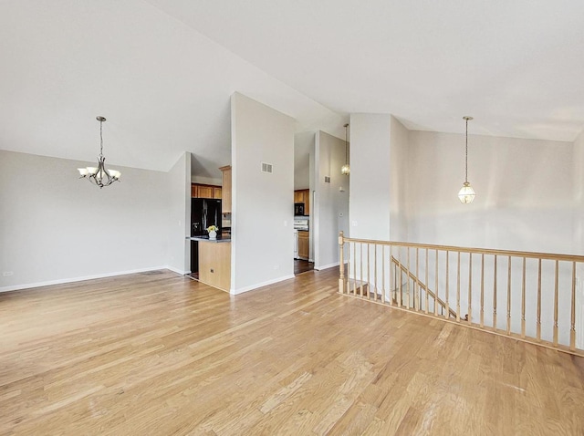 spare room featuring a notable chandelier, light hardwood / wood-style floors, and high vaulted ceiling