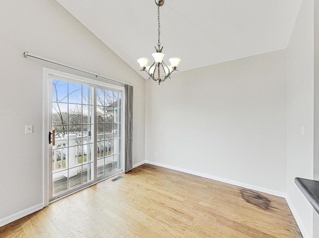 unfurnished dining area with wood-type flooring, a chandelier, and vaulted ceiling