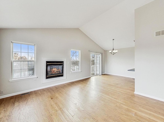 unfurnished living room with an inviting chandelier, vaulted ceiling, and light wood-type flooring